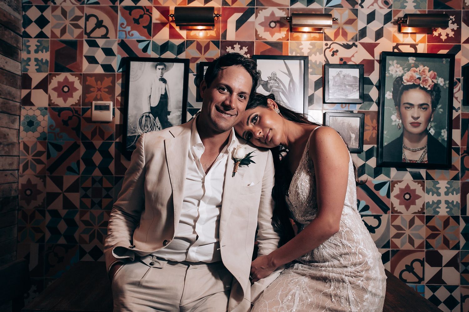 Wedding celebration in a rustic venue with decorative tiled walls and moody lighting.