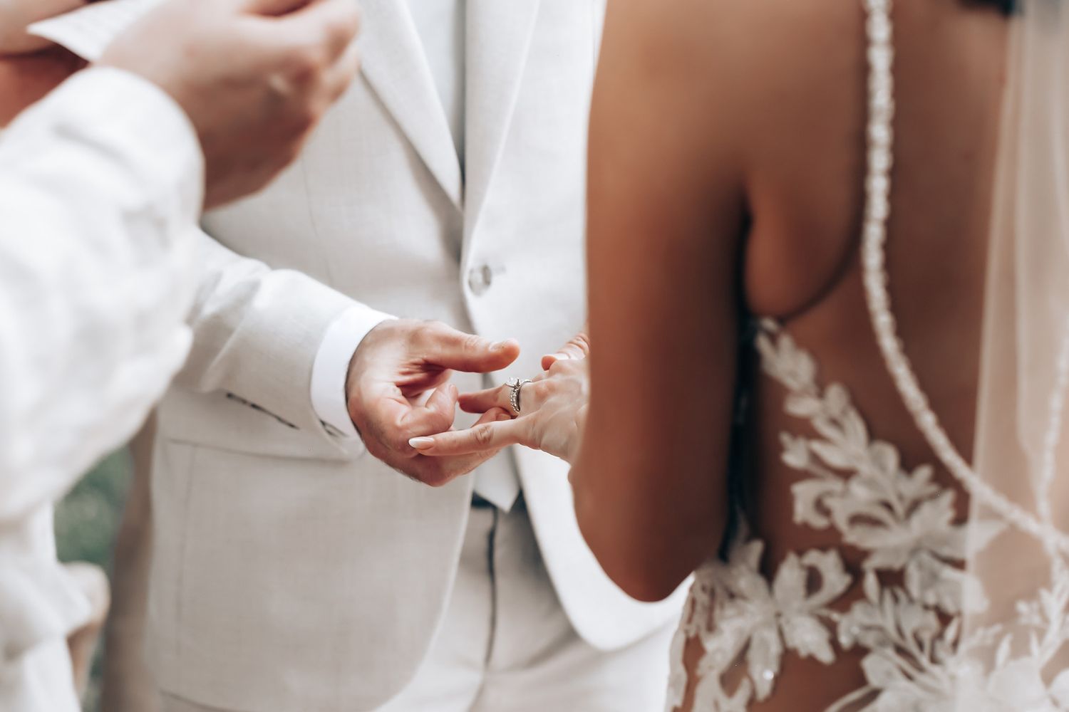 Intricate details of a white lace wedding dress against a neutral background.