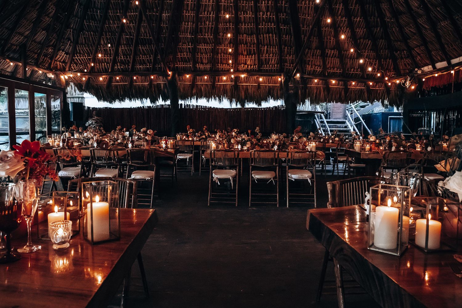 Elegant reception venue with thatched roof and ambient lighting creating a warm, romantic atmosphere.