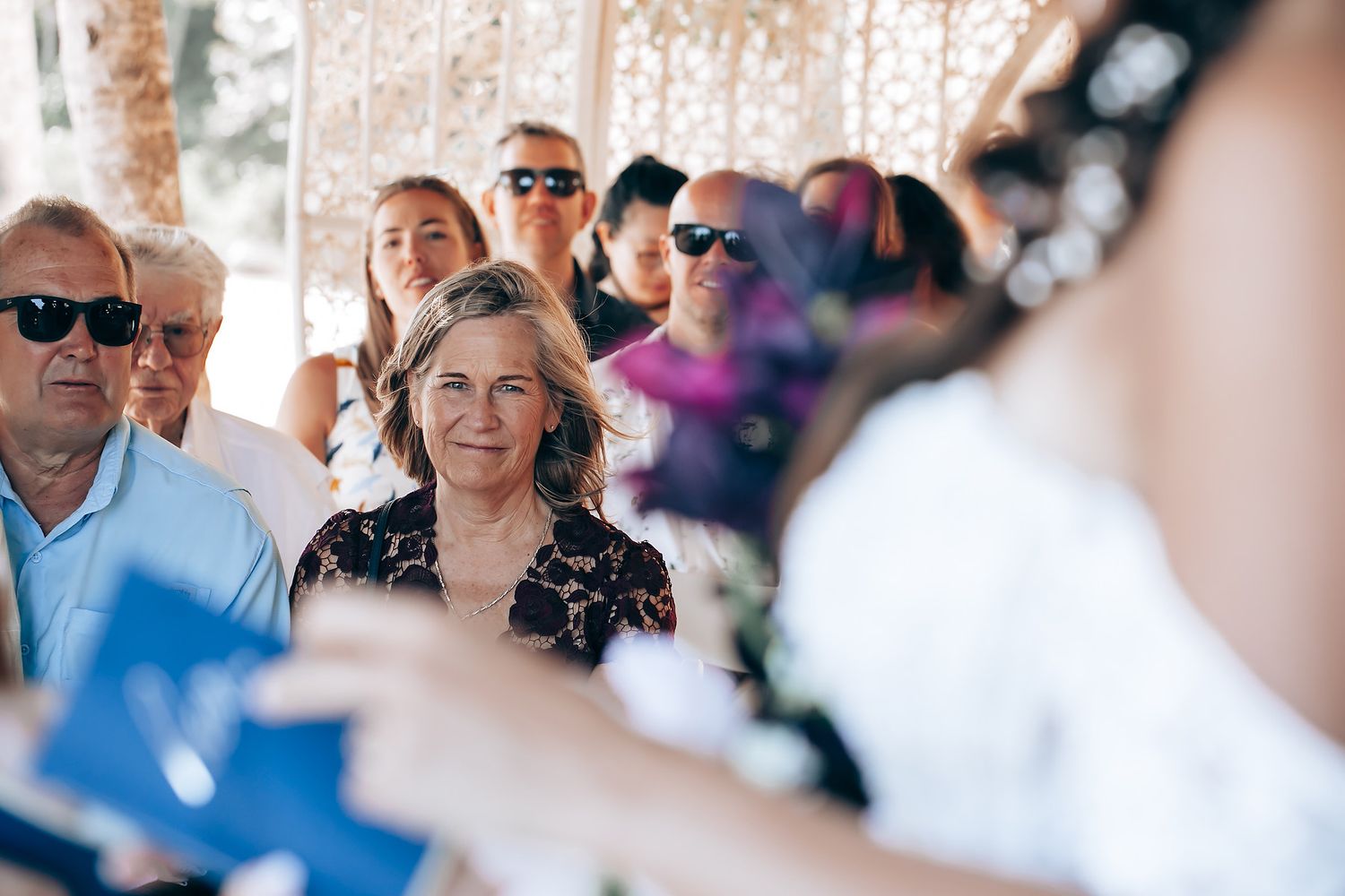 Wedding guests gather under an elegant covered outdoor venue during a celebration.