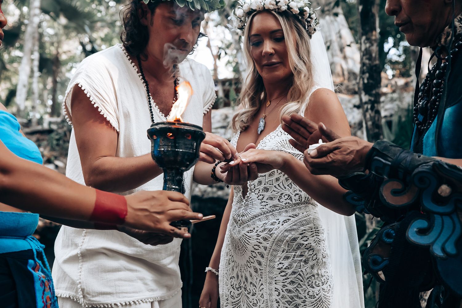 Two people in white dresses share a joyful moment while holding drinks outdoors in a garden setting.