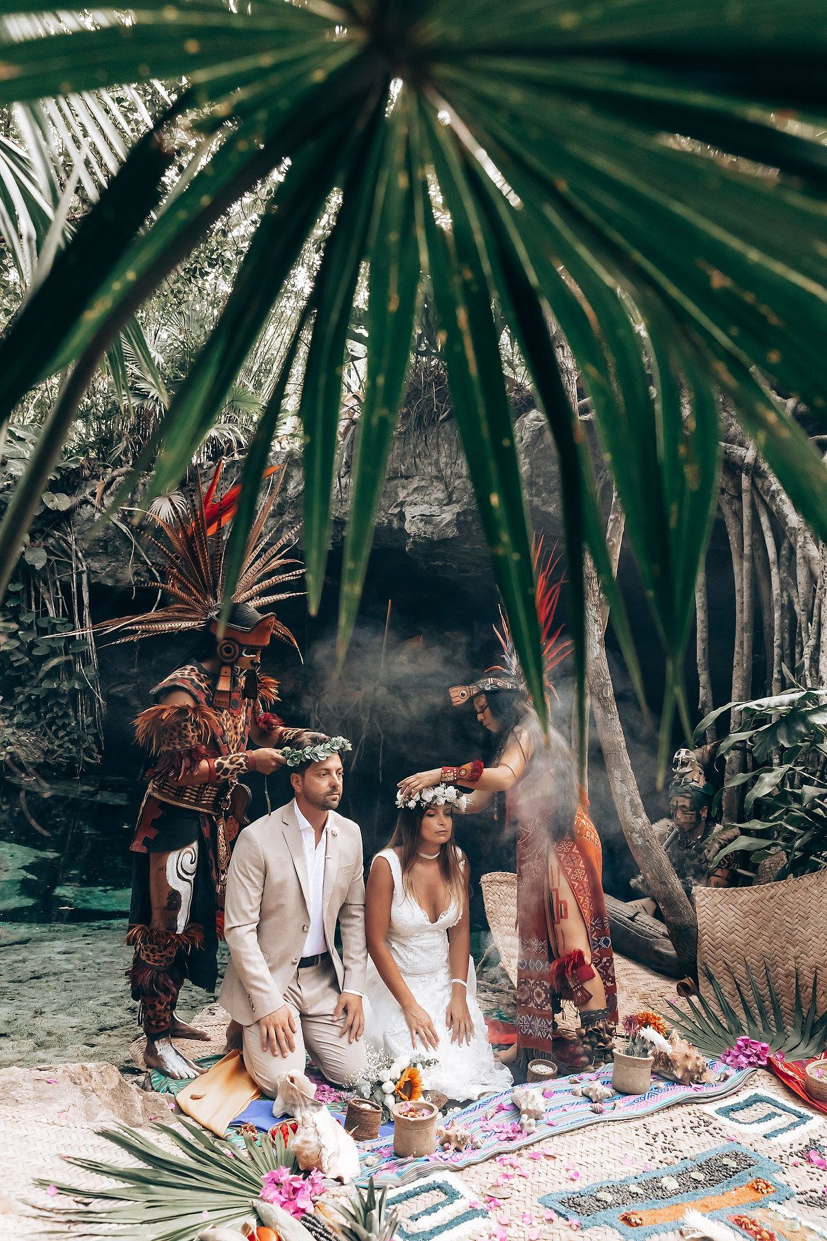A traditional spiritual ceremony takes place in a tropical garden setting with palm fronds and decorative elements.
