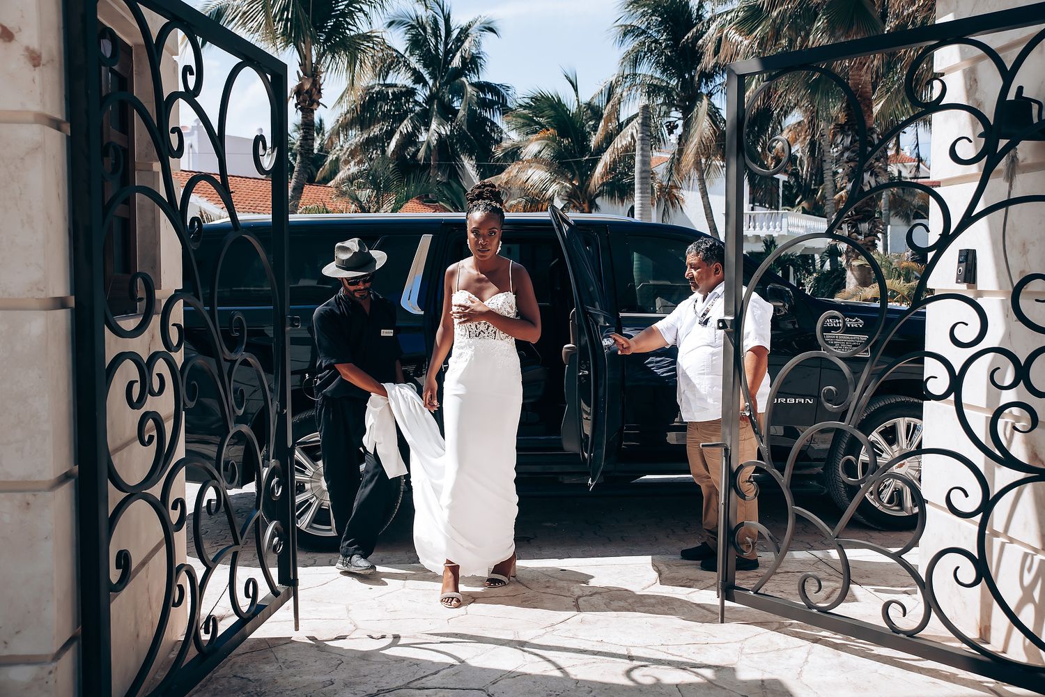 A scenic outdoor wedding venue with palm trees and ornate iron railings.