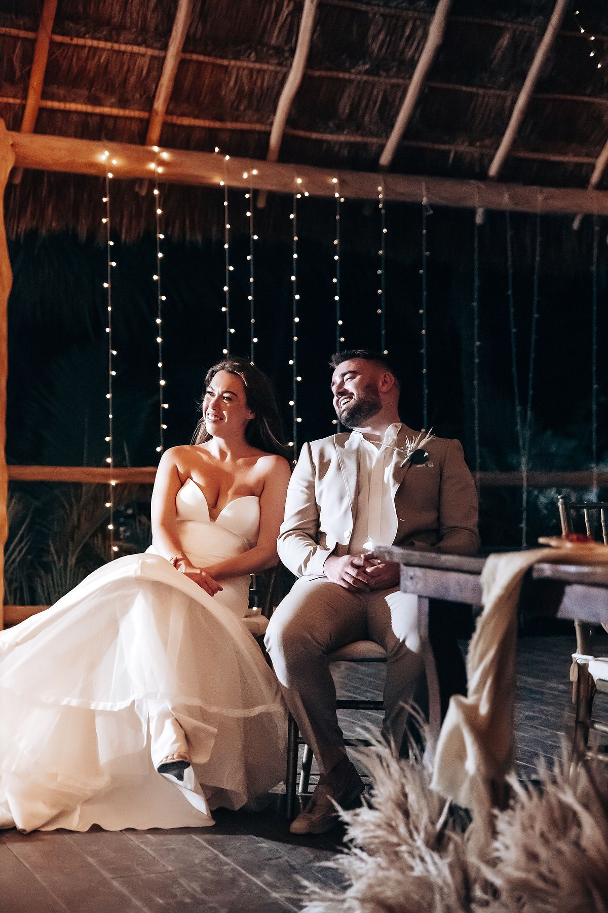 Newlyweds share intimate moments during their first dance at a rustic barn wedding reception with twinkling lights.