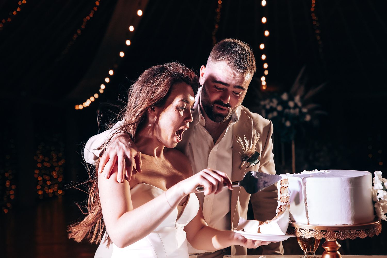 Newlyweds share their first dance together at a romantic reception venue with twinkling lights.