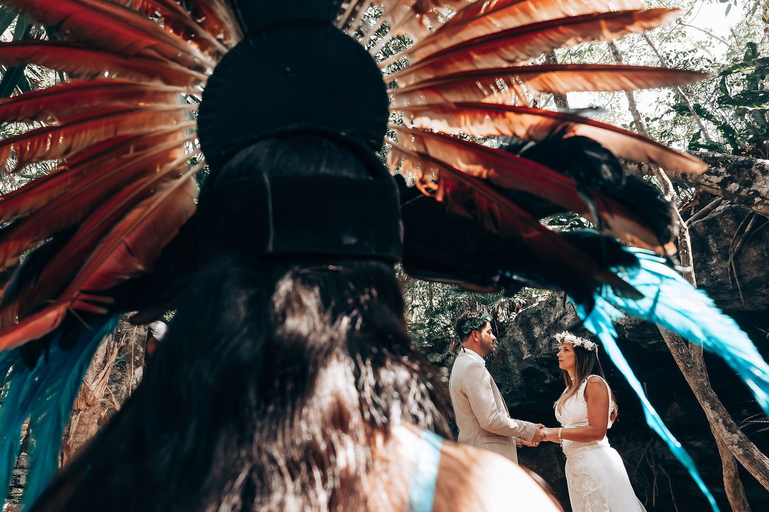 Ceremonial headdress with vibrant red and blue feathers against natural forest backdrop.
