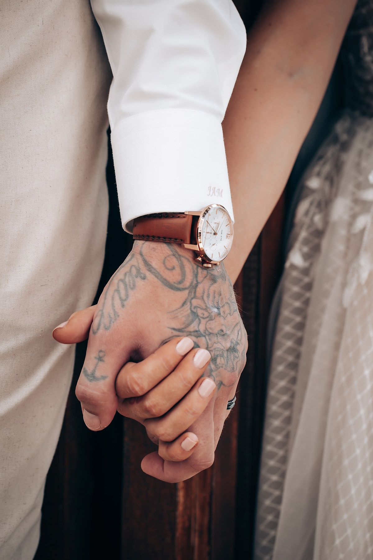 Close-up of tattooed hands holding together during a wedding ceremony.