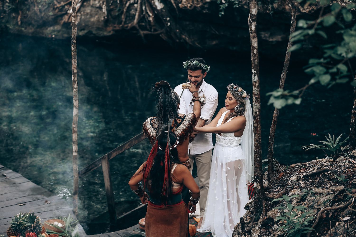 A wedding ceremony blends modern and indigenous traditions in a forest environment.