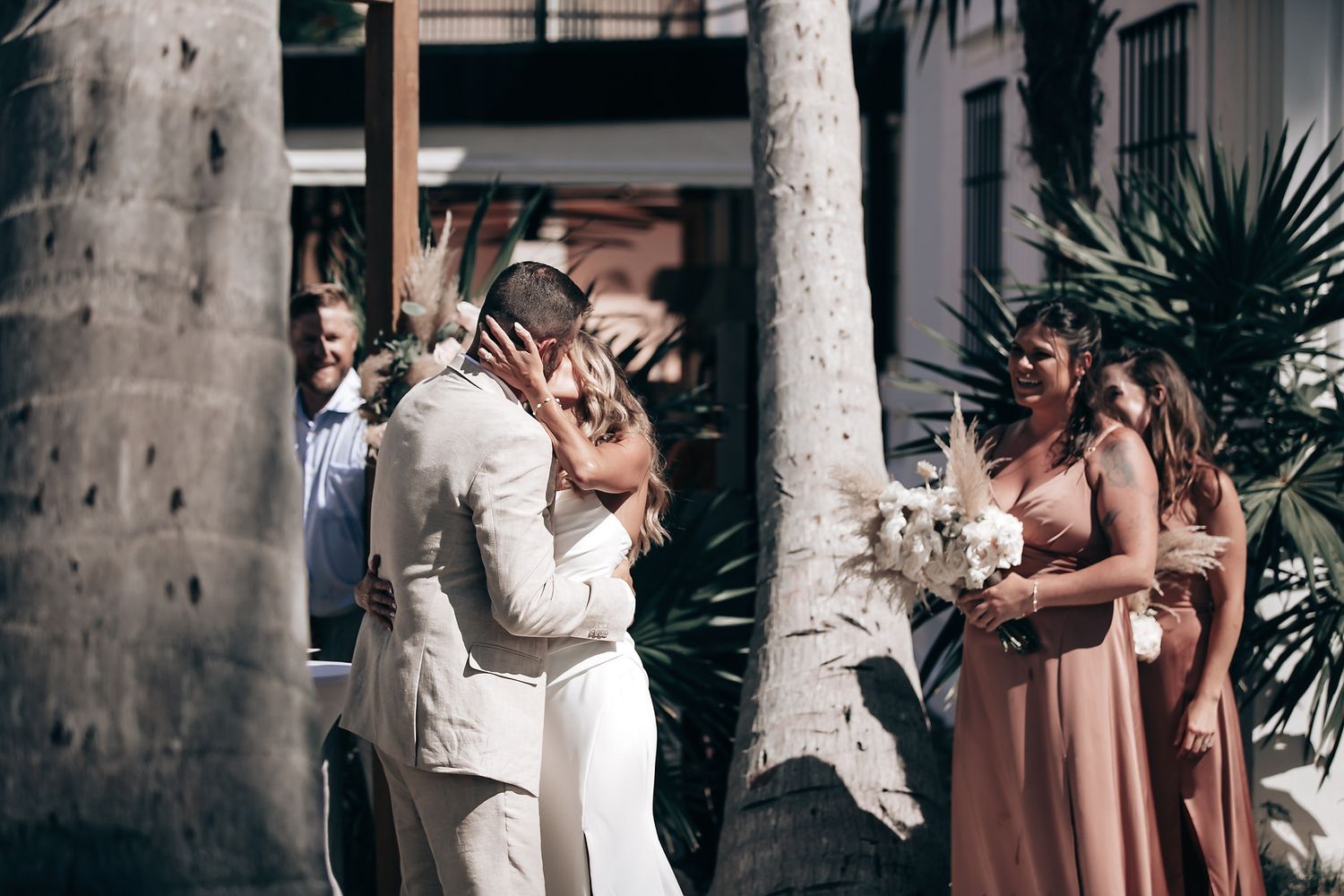 A couple embraces and kisses in an intimate outdoor wedding setting.