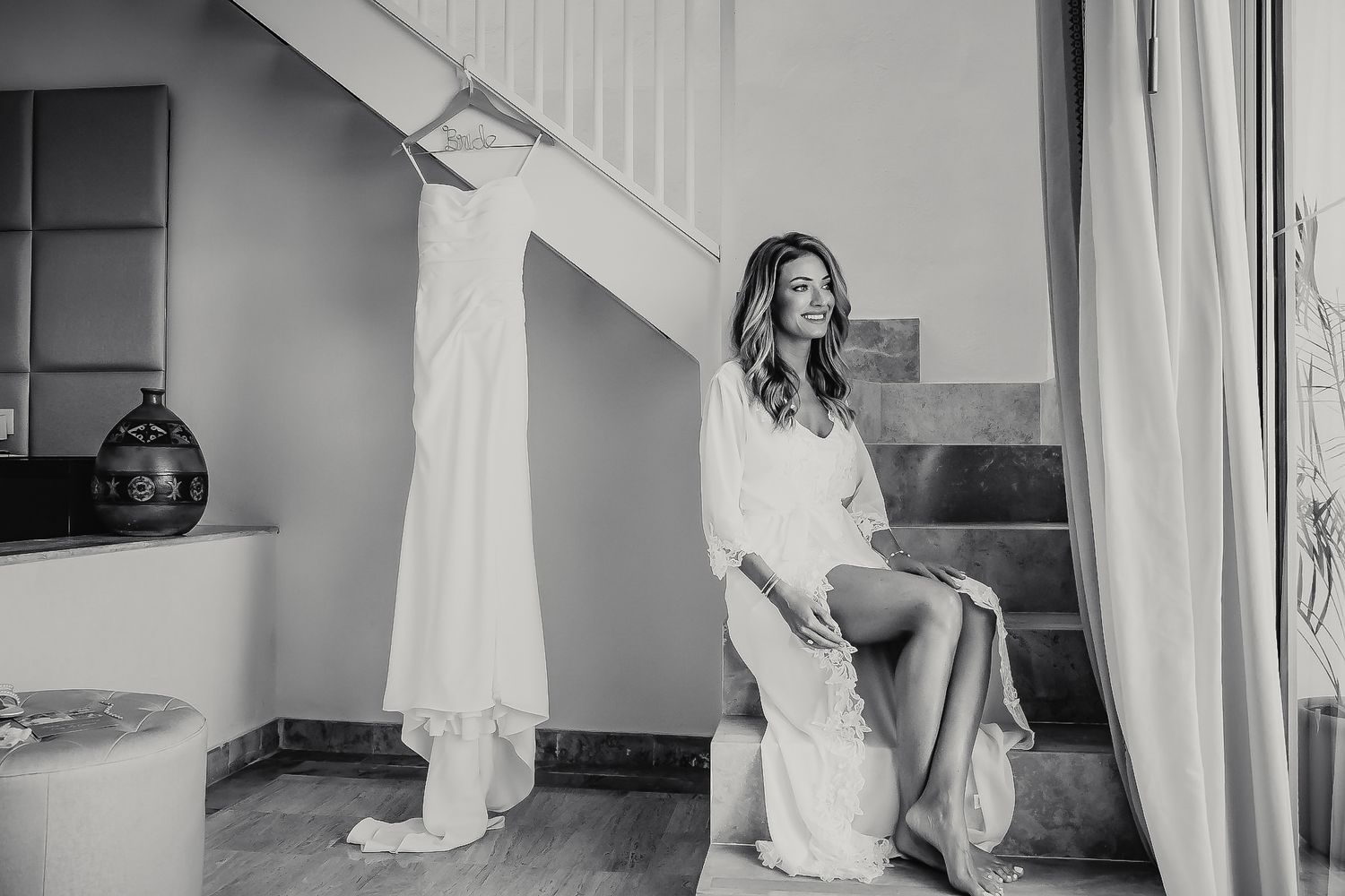A woman in a white dress sits on a staircase, looking away from the camera.