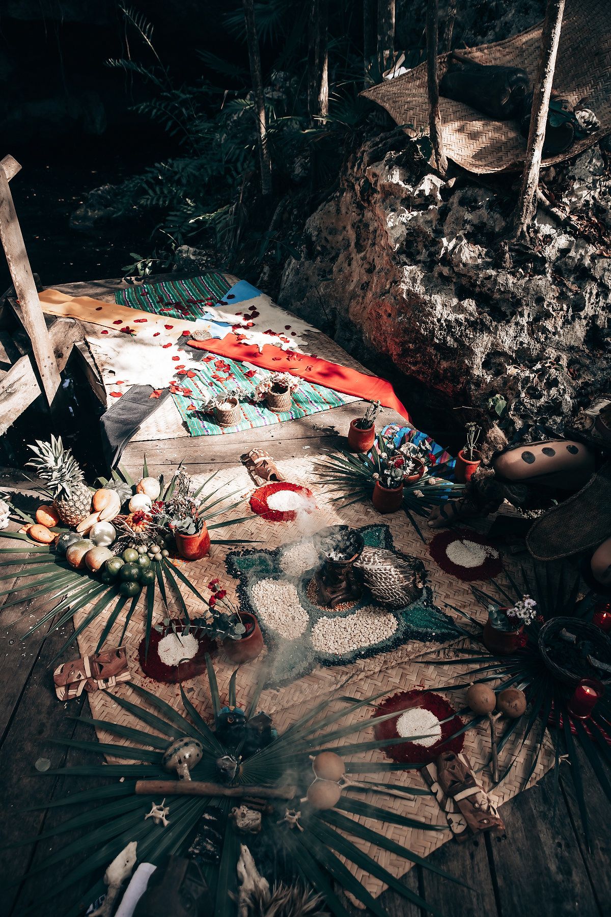Decorative items and ceremonial objects arranged on ground in dark moody lighting with red accents.