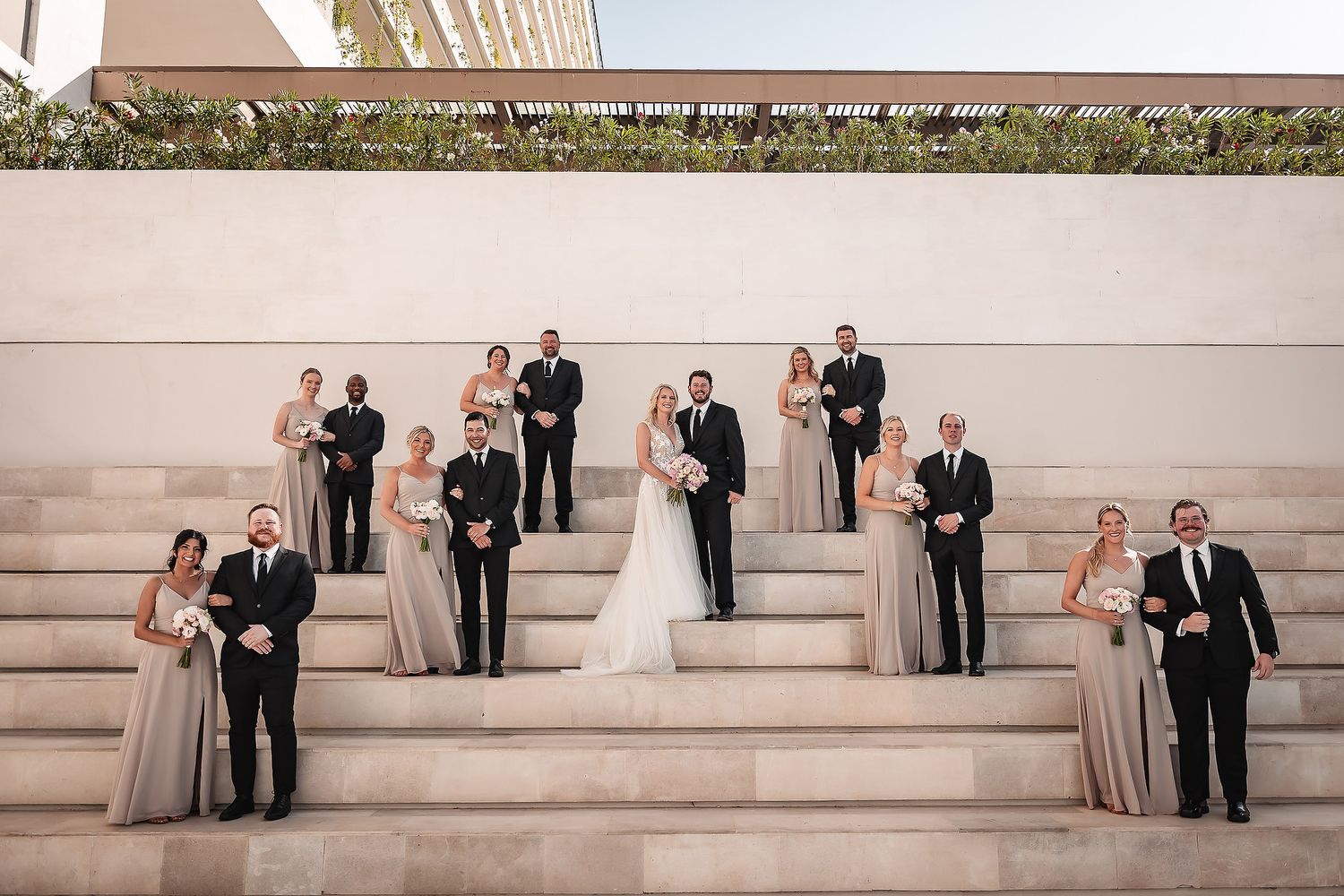 Wedding party poses on outdoor stone steps in formal attire.