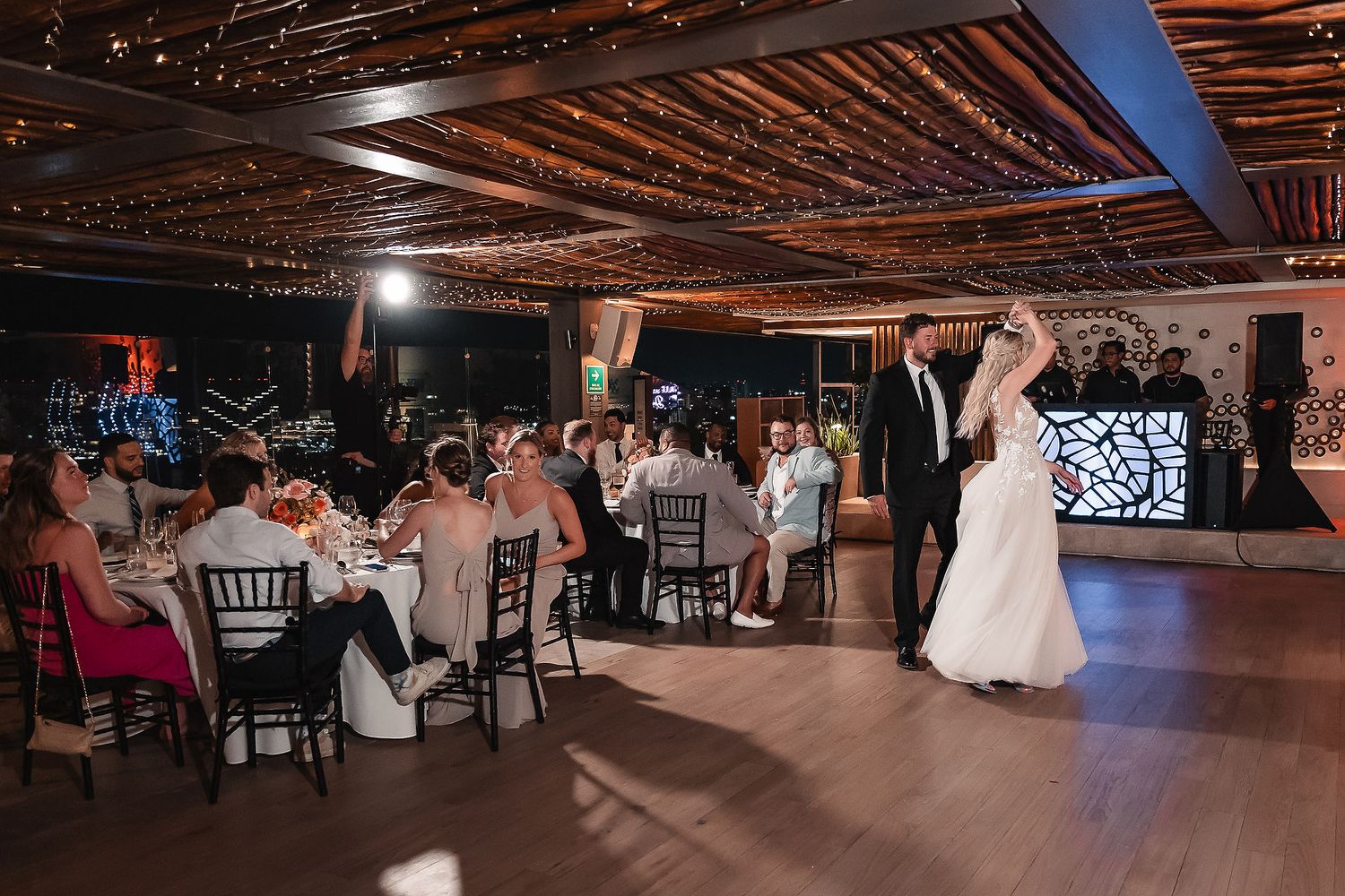 Wedding reception venue with rustic wooden ceiling and warm lighting creates an intimate atmosphere.