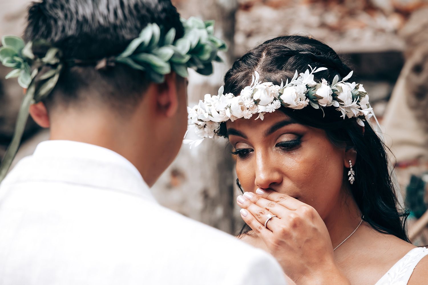Intimate wedding ceremony moment captured in a natural forest setting with floral decorations.
