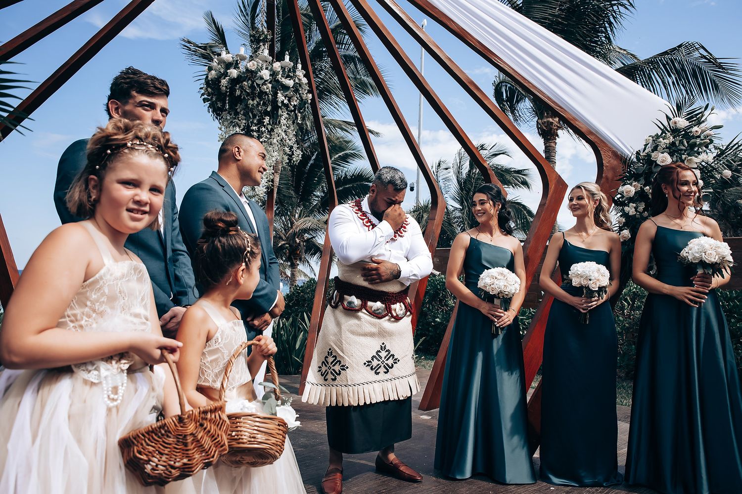Wedding guests seated in rows at an outdoor ceremony with palm trees.