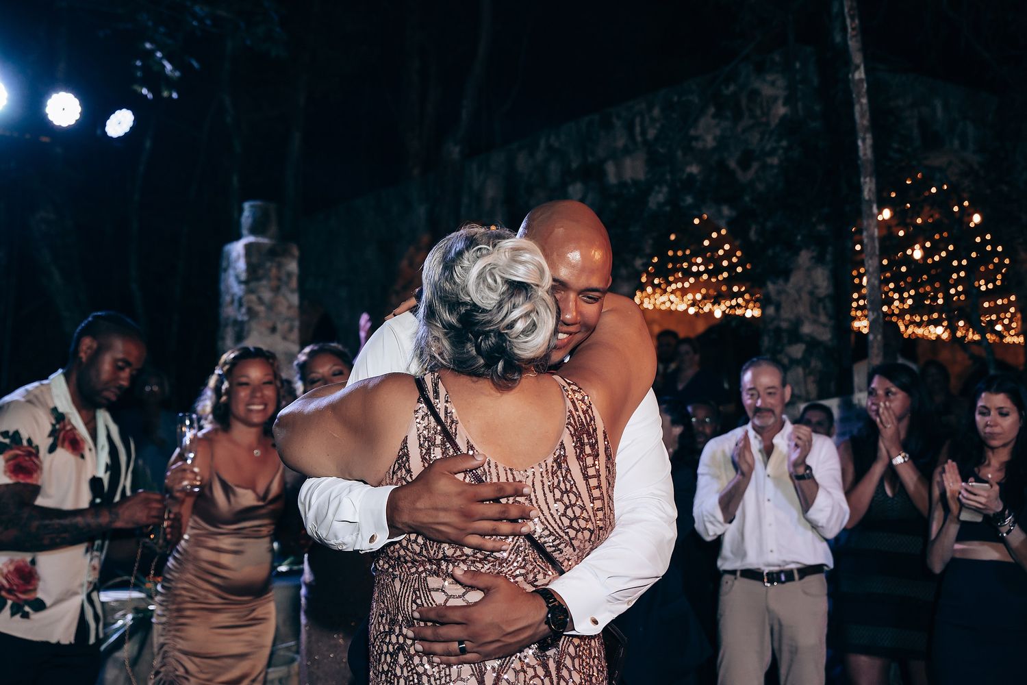 Intimate slow dance moment at outdoor evening wedding reception with string lights.