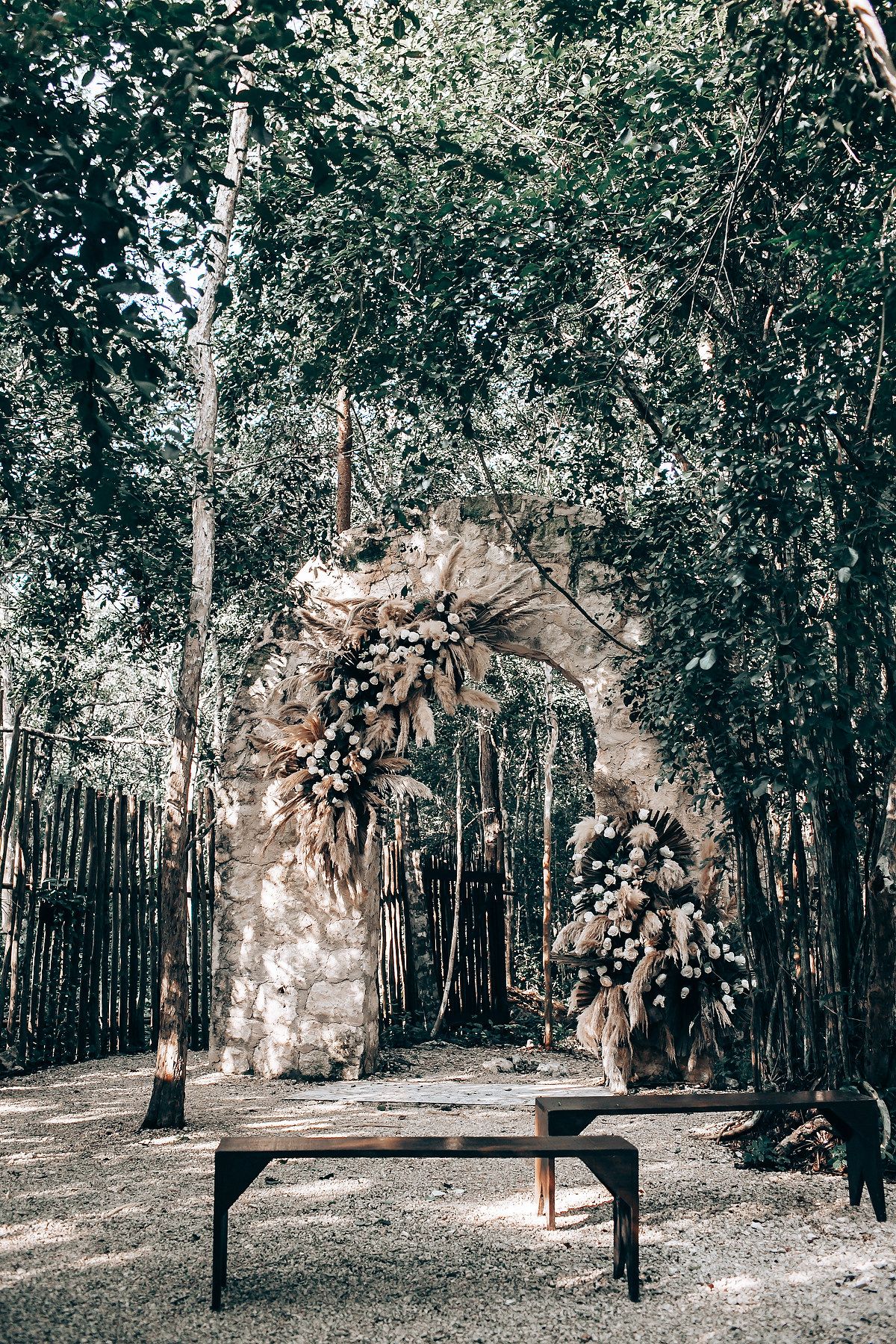 Outdoor wedding ceremony setup in a wooded area with floral arch decorations.