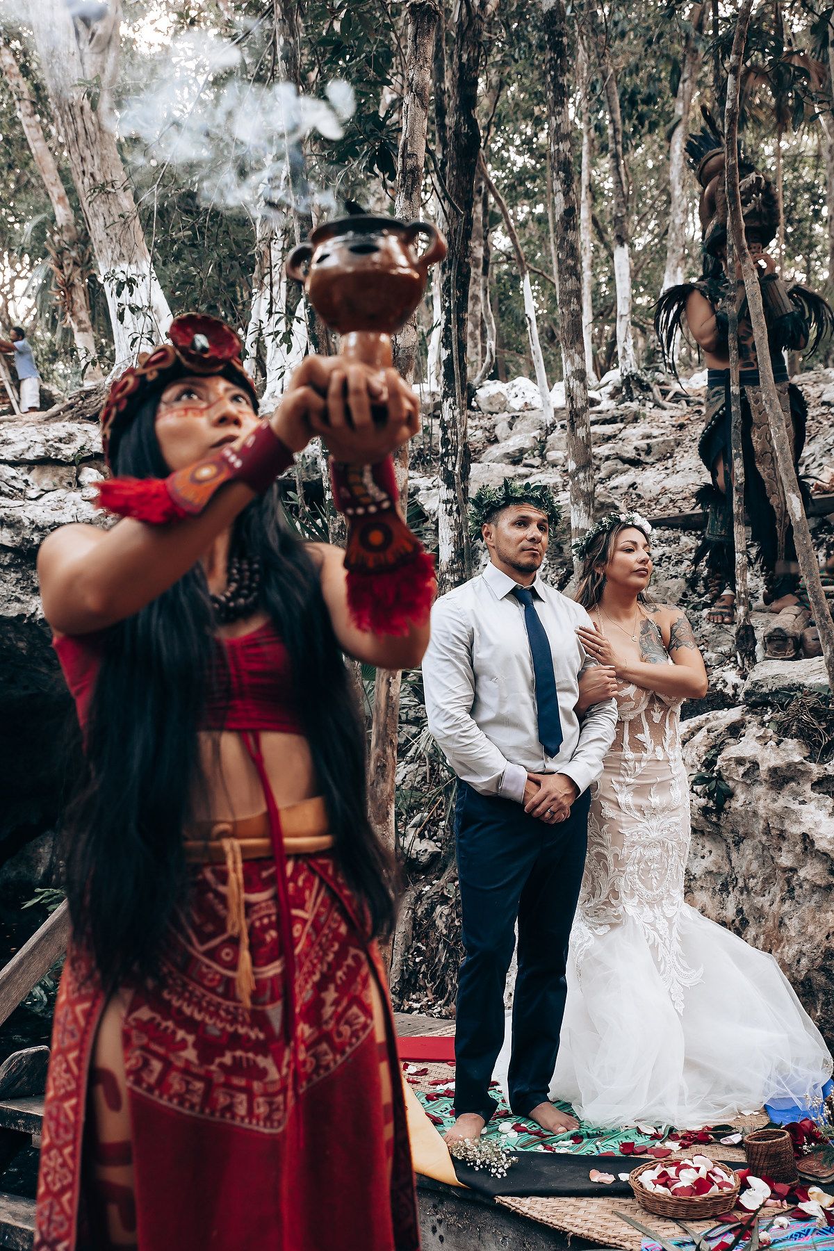 A traditional ceremony being performed by a person in red attire during an outdoor wedding.