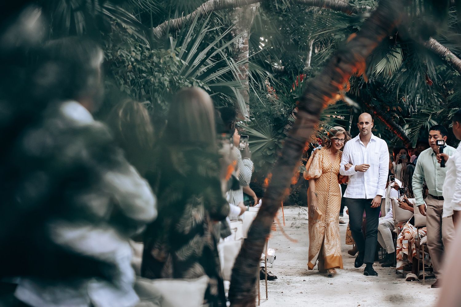 Wedding guests mingling in an outdoor tropical garden setting.