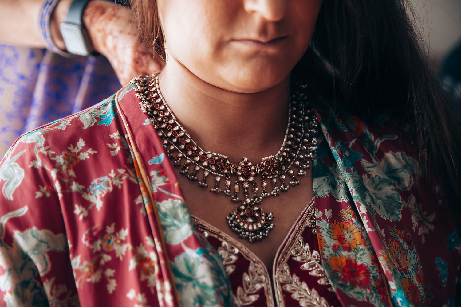 Close-up of ornate silver statement necklace worn with colorful patterned fabric.
