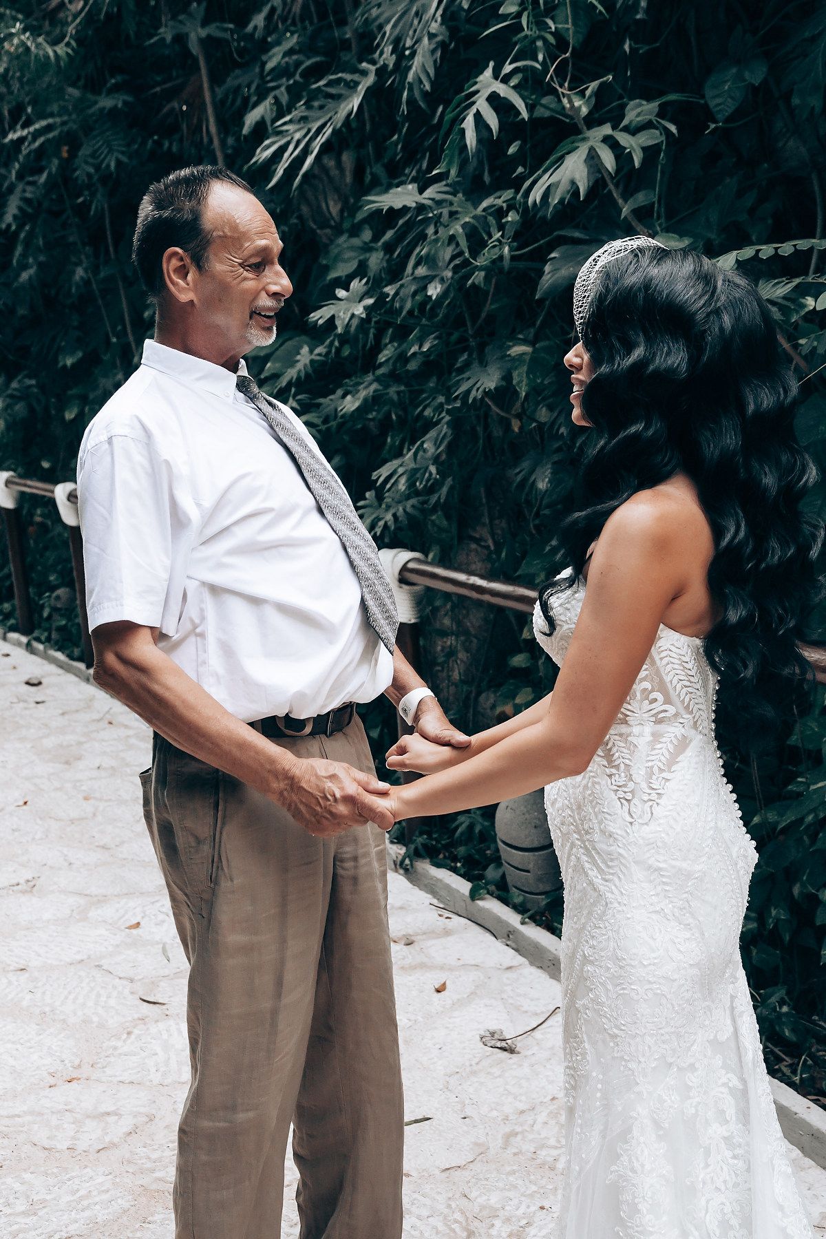 A tender moment between two people in a tropical garden setting with lush greenery in the background.