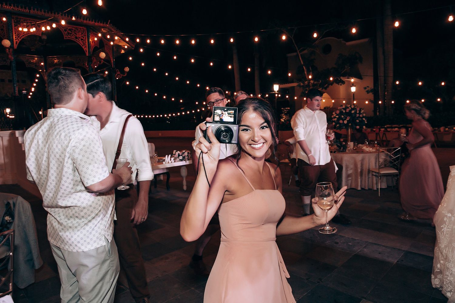 Festive string lights create a magical atmosphere at an outdoor evening reception.