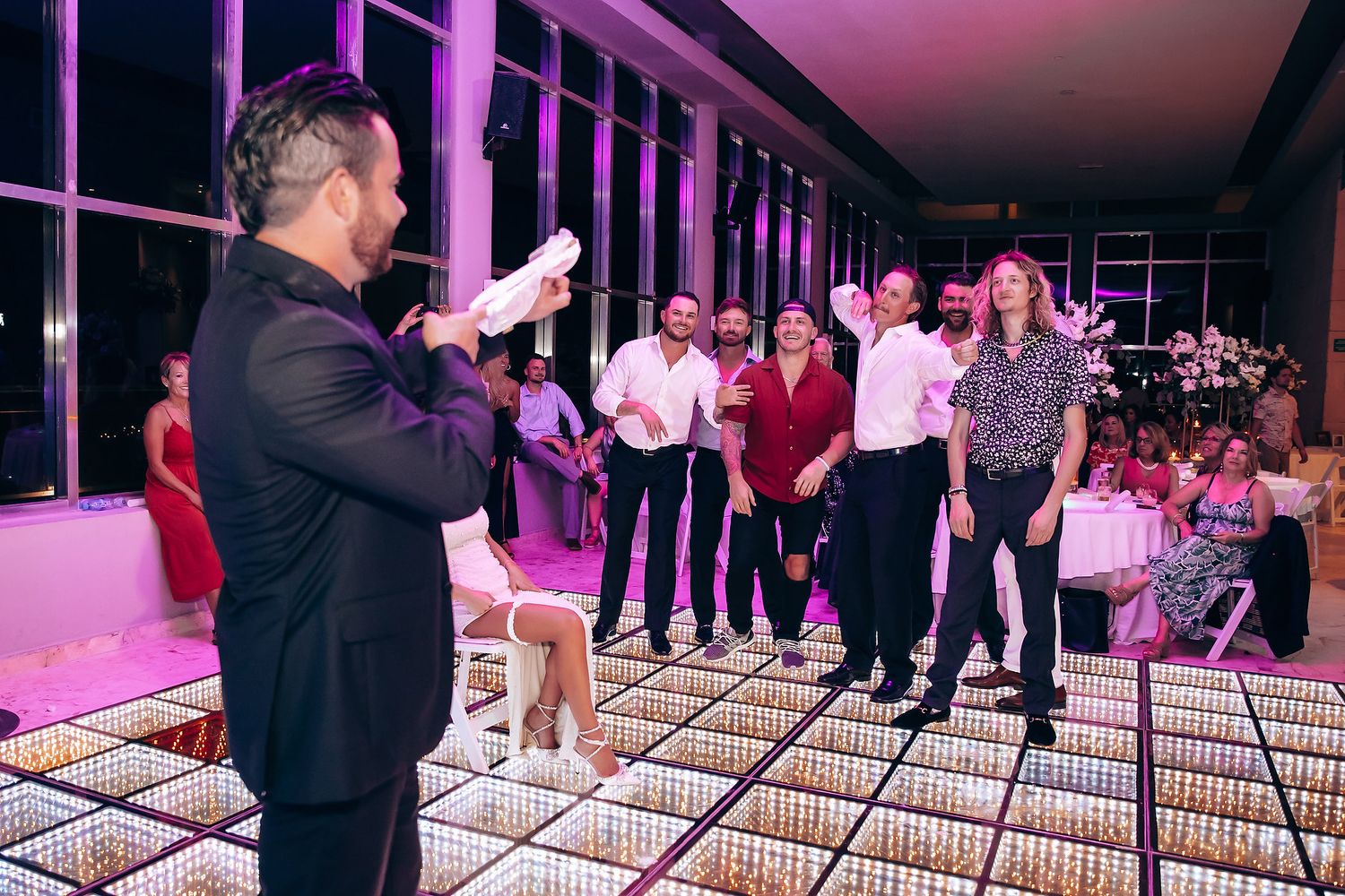 Wedding reception venue with illuminated dance floor and pink ambient lighting.