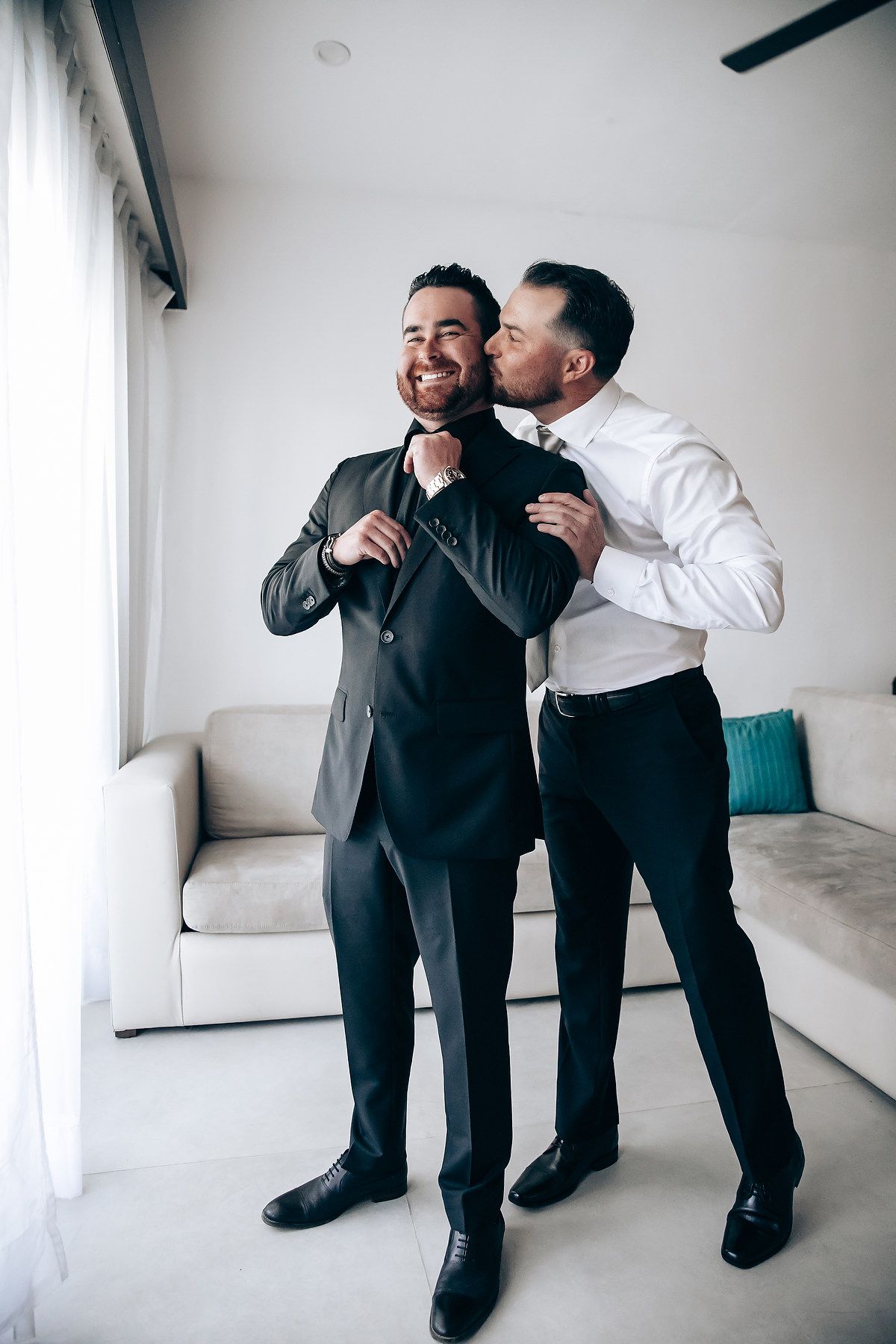 Two people sharing an intimate moment while getting ready in formal attire.