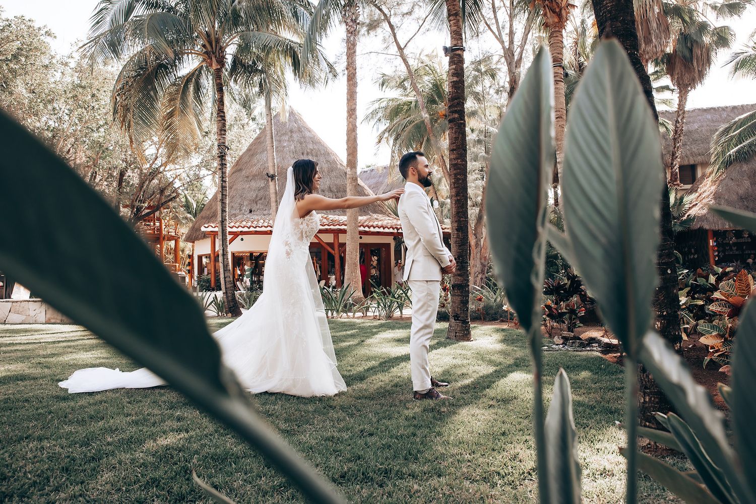 Wedding ceremony setup in a tropical garden with palm trees and natural lighting.