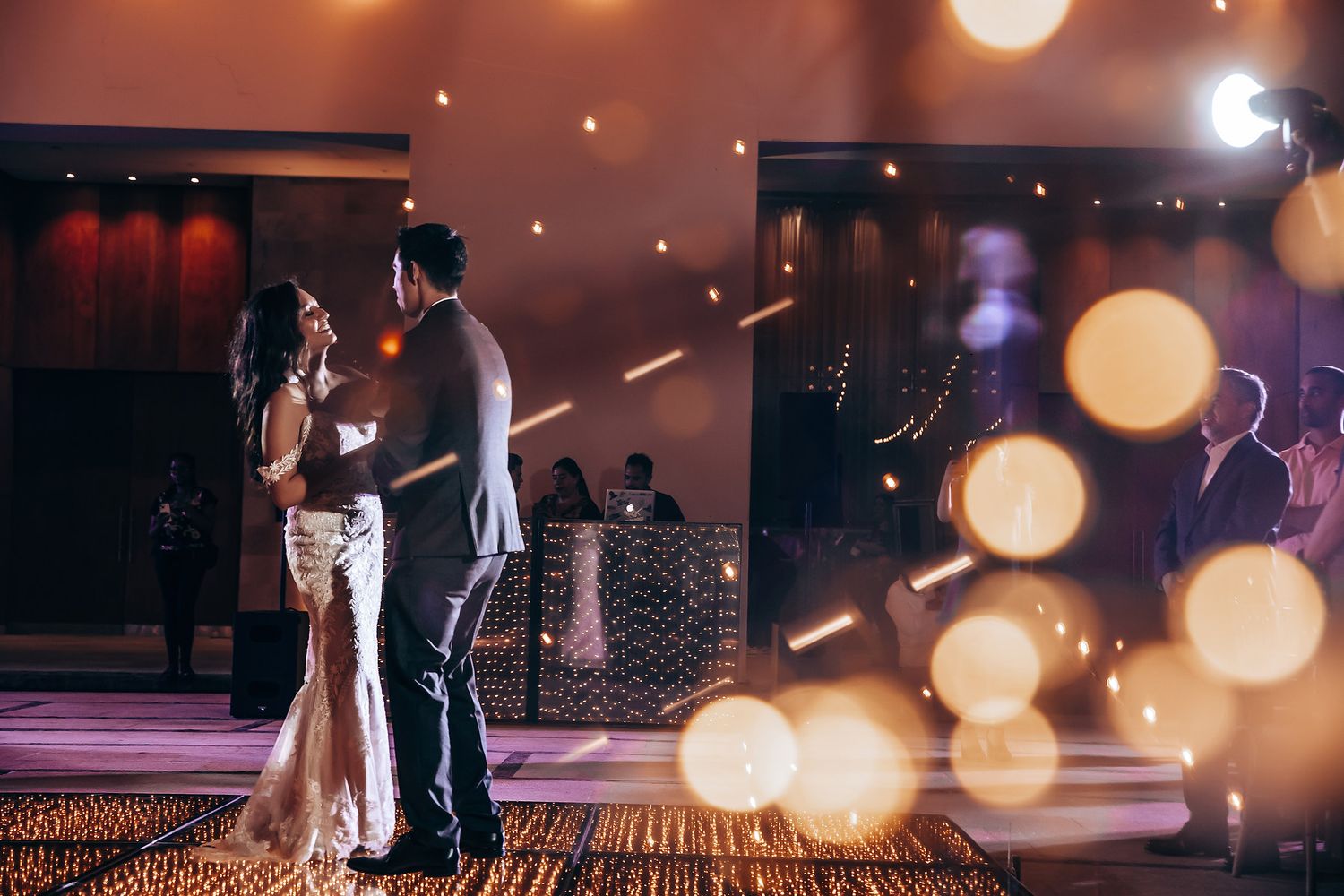 Romantic first dance moment captured with dreamy bokeh lighting effects.