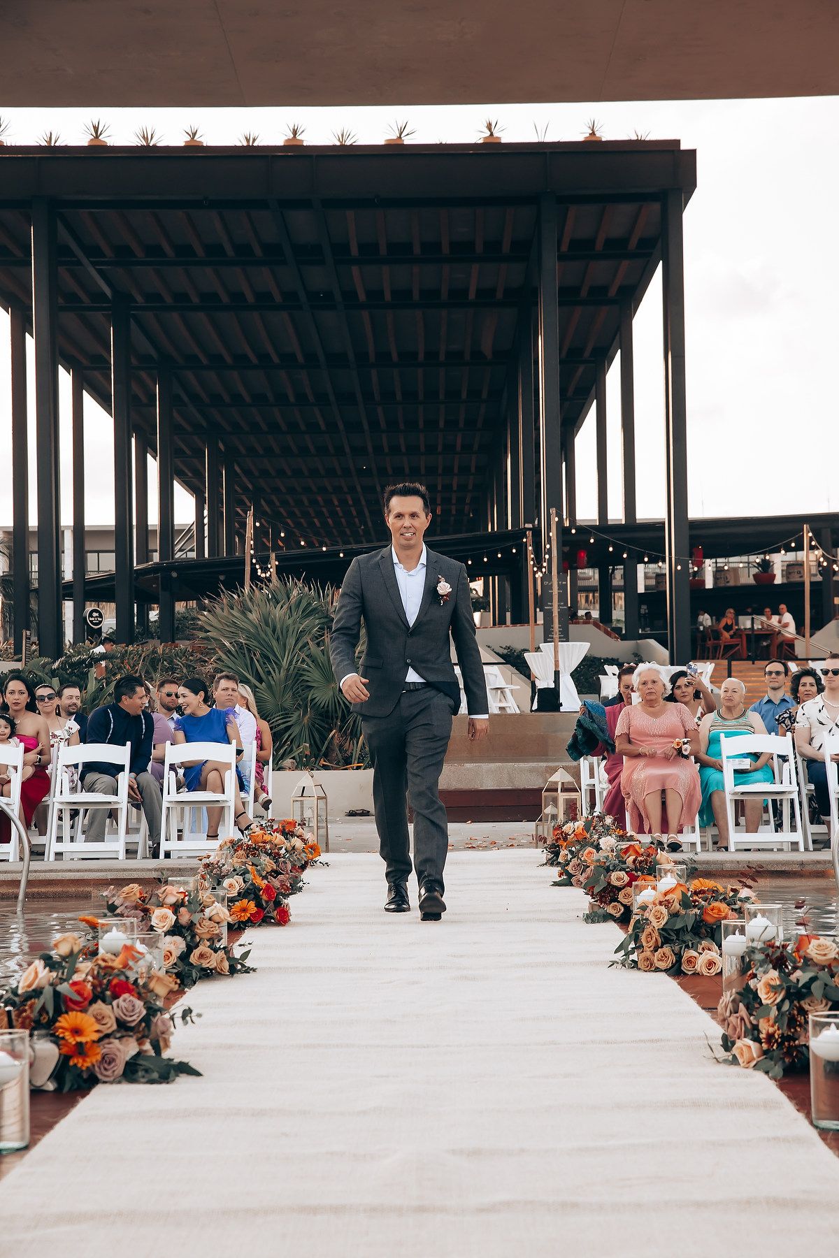 Modern outdoor wedding venue with covered pavilion decorated with autumn floral arrangements.