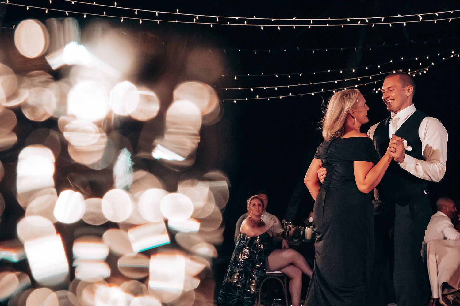 Bokeh lights create a dreamy atmosphere at an evening wedding reception.
