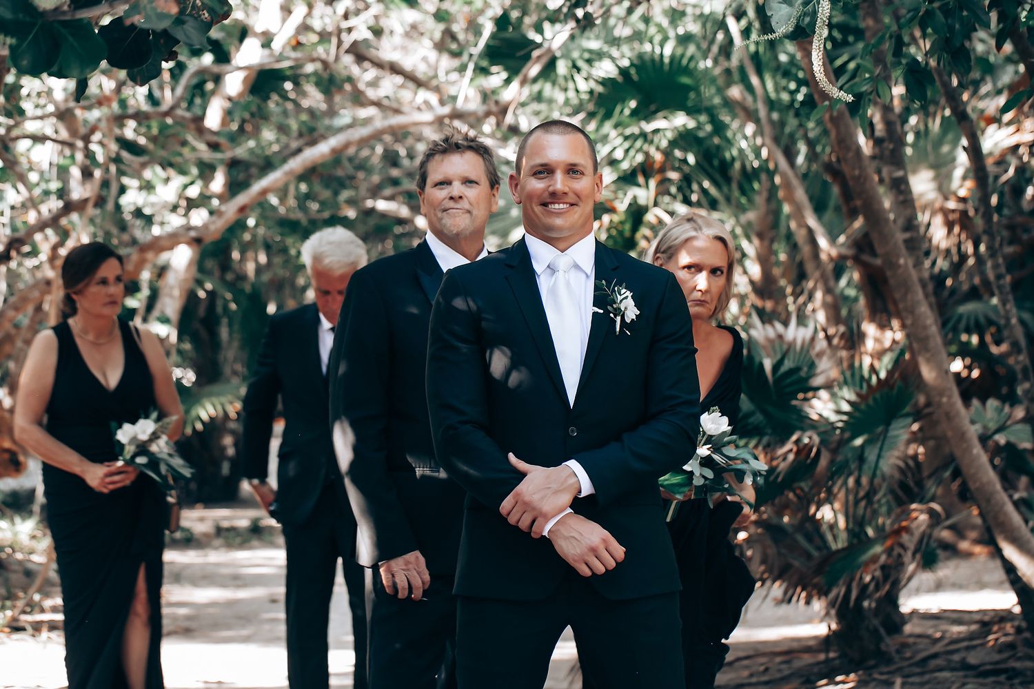 Wedding guests seated in formal attire during an outdoor garden ceremony.
