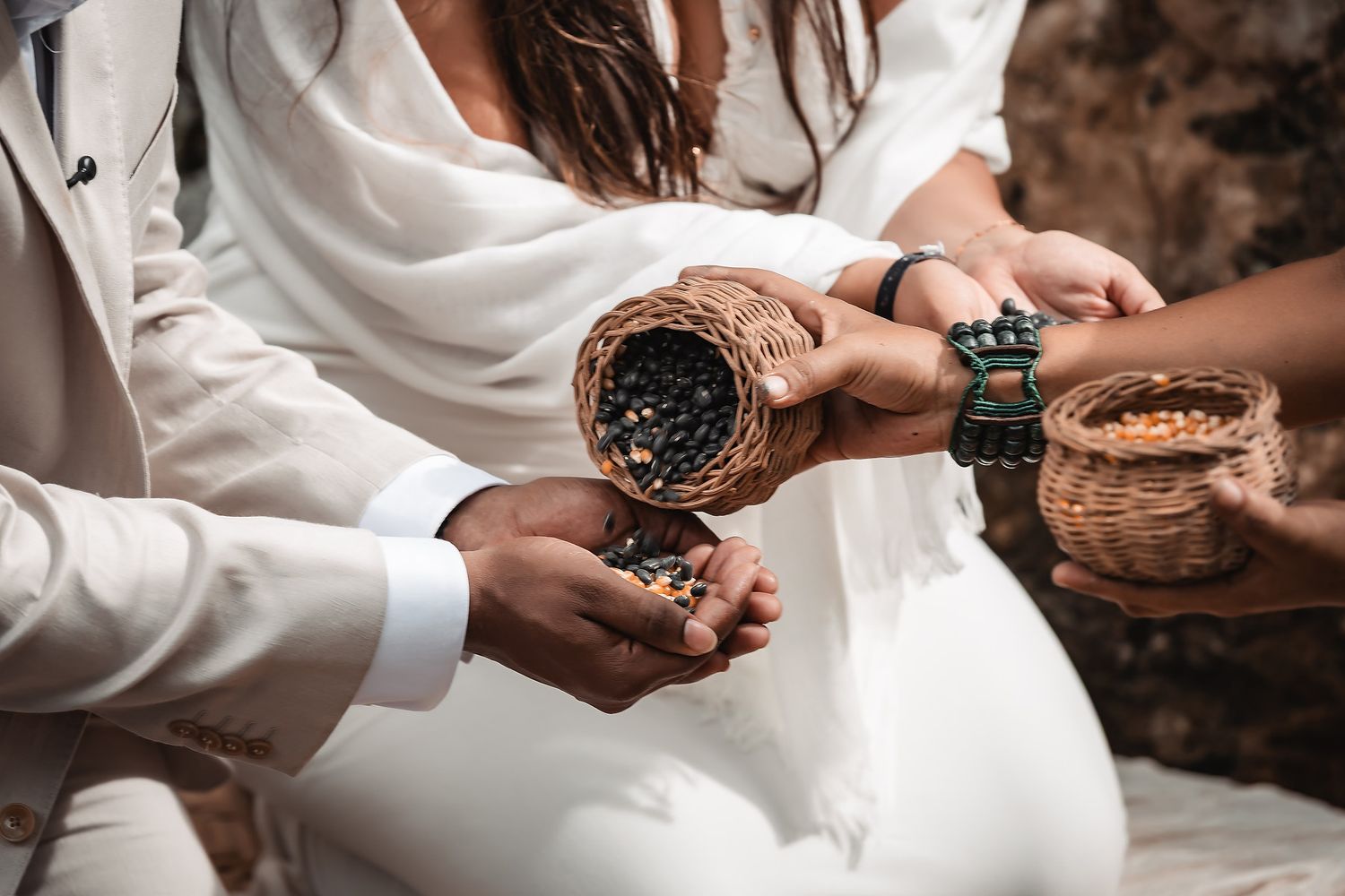 Hands pouring ceremonial elements from decorative vessels during a ritual.