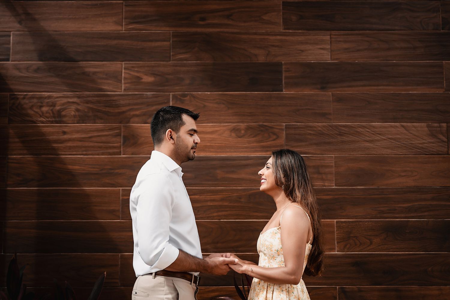 Couple sharing an intimate moment against a dark wood paneled wall.