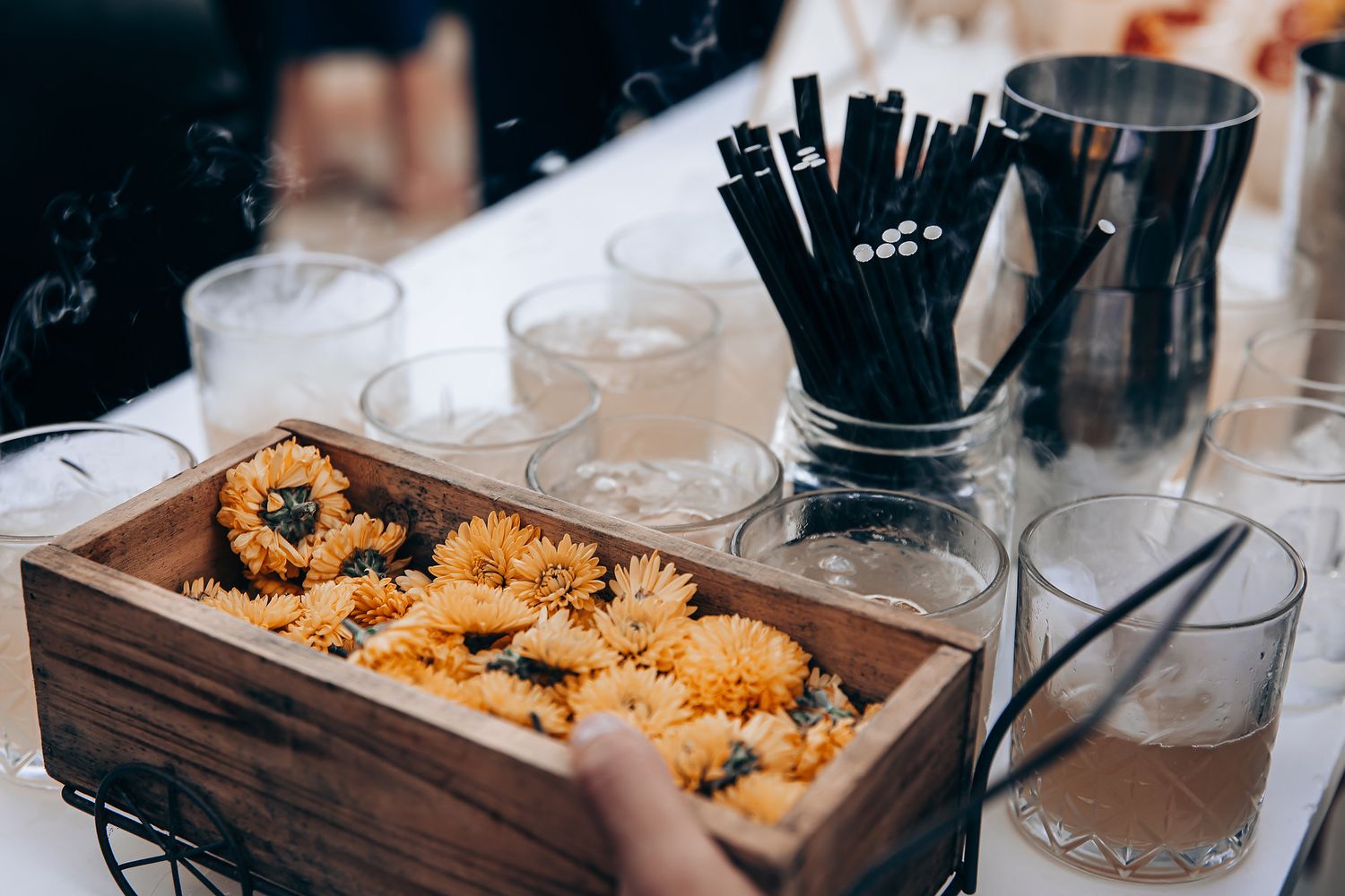 Wooden serving tray filled with golden fried appetizers and black chopsticks in a holder on a dining table.
