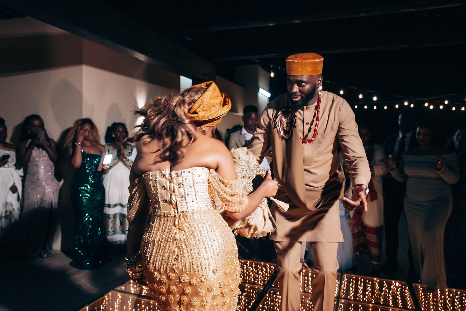 Reception guests dancing and mingling under twinkling lights at an evening wedding celebration.