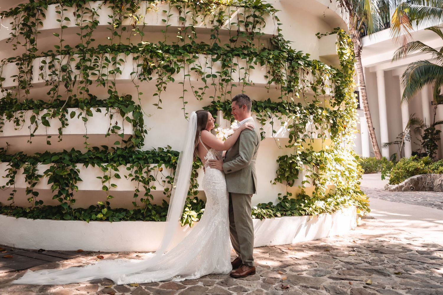 Romantic first look sequence captured in a garden setting with white walls and green climbing vines.