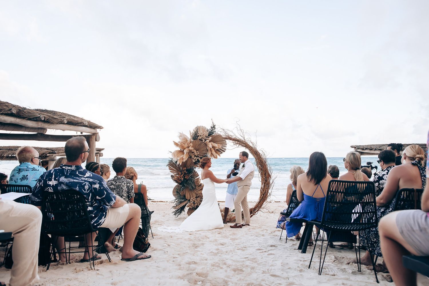 Beachfront wedding ceremony with chairs arranged on sand and ocean backdrop.