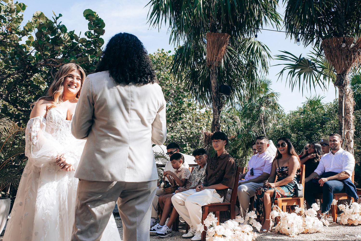 Outdoor wedding ceremony with palm trees and natural decor.
