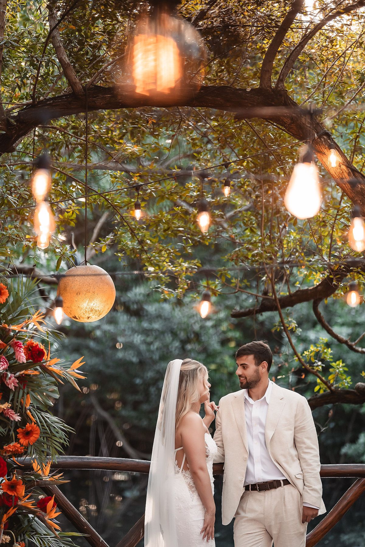 Romantic wedding photography with warm lighting from hanging lanterns in a garden setting.