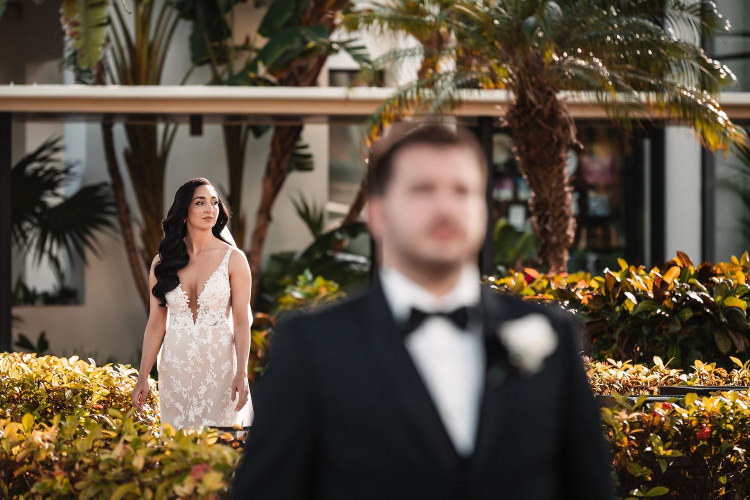 Wedding party poses outdoors with tropical plants and yellow flowers creating a vibrant backdrop.