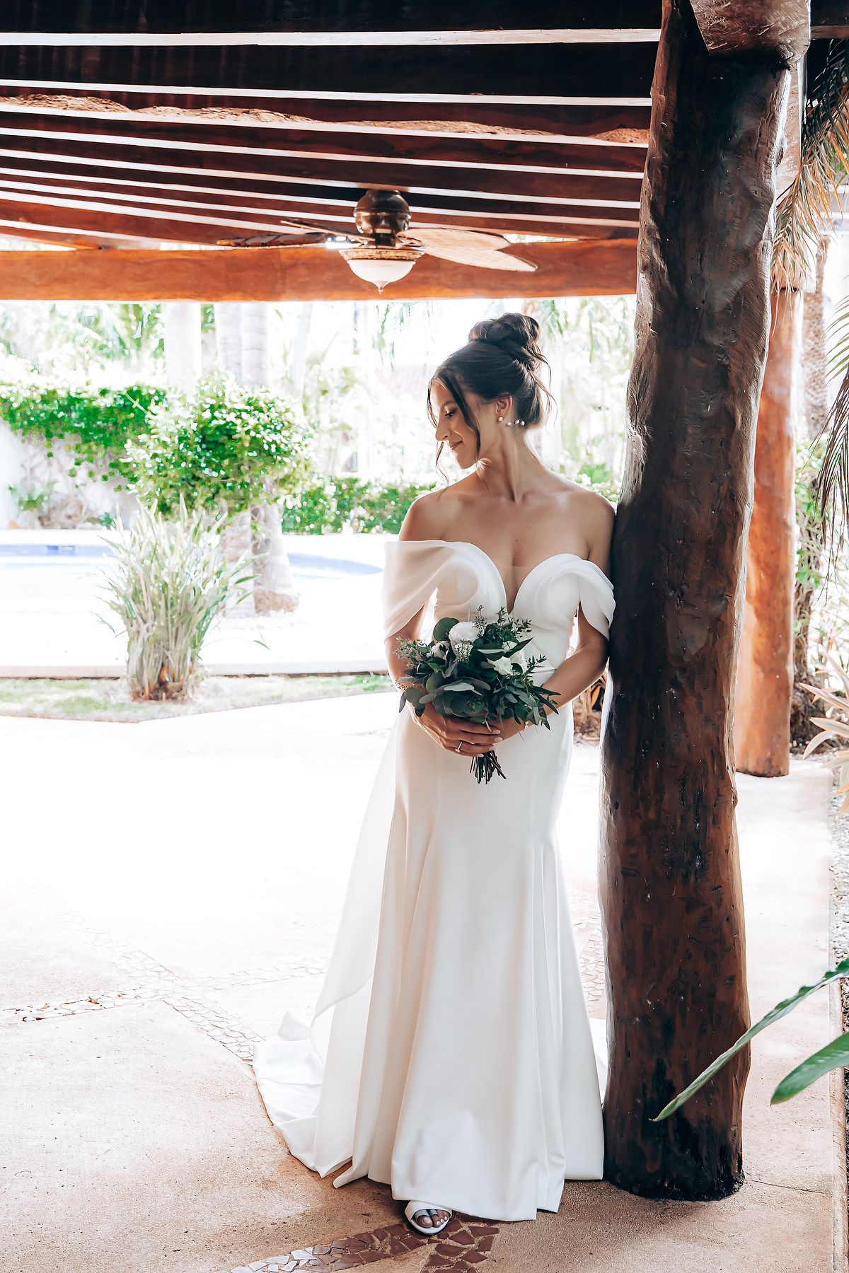 Elegant wedding portraits taken under a rustic wooden pavilion with natural lighting.