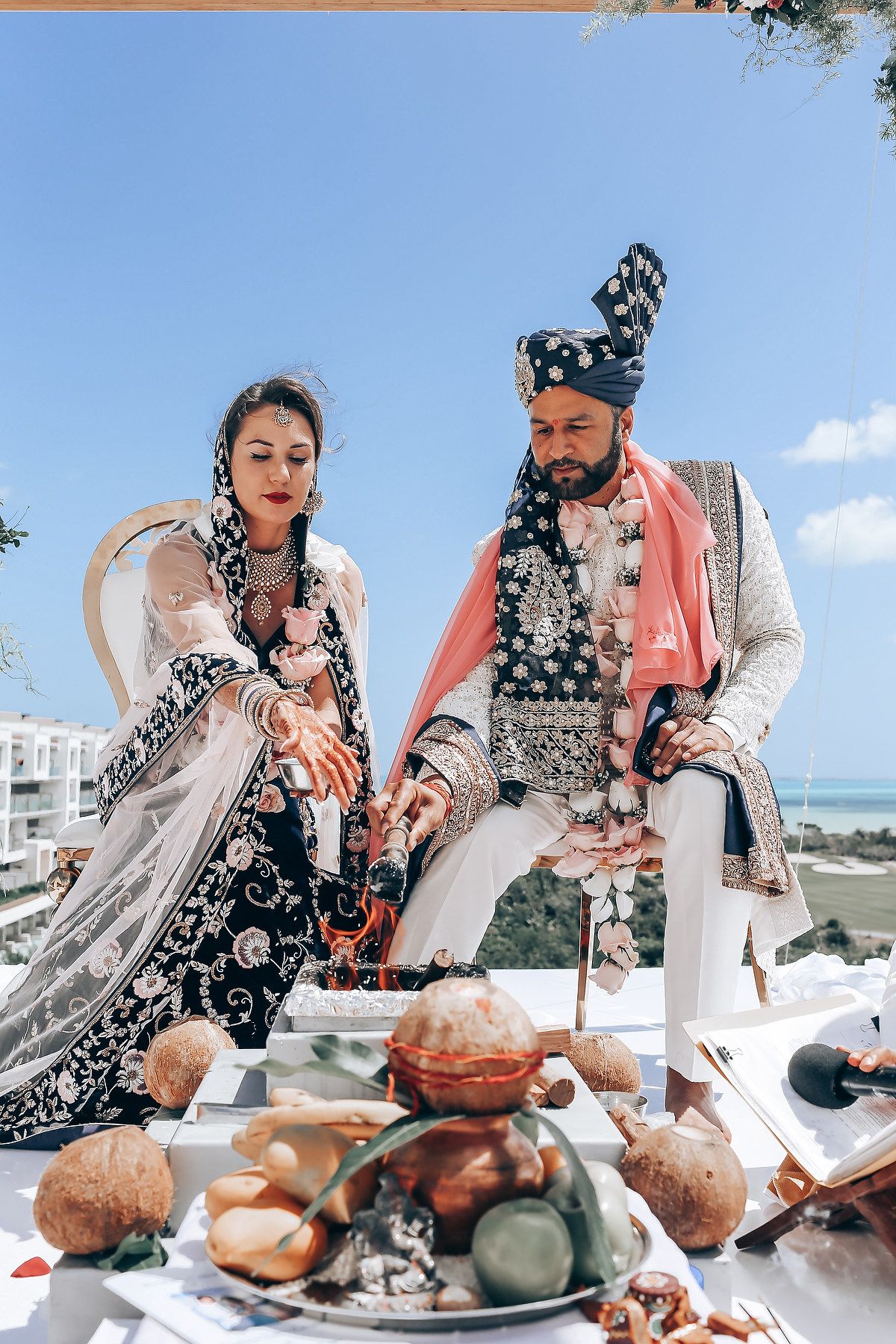 Traditional wedding ceremony participants share a meal at an outdoor table with ocean views.