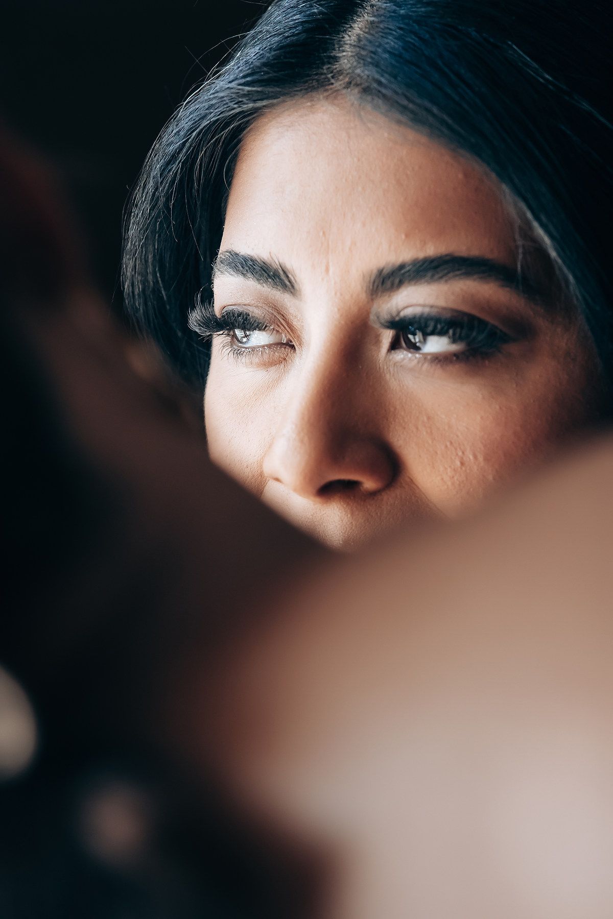 Close up portrait showing dramatic eye makeup in moody lighting.