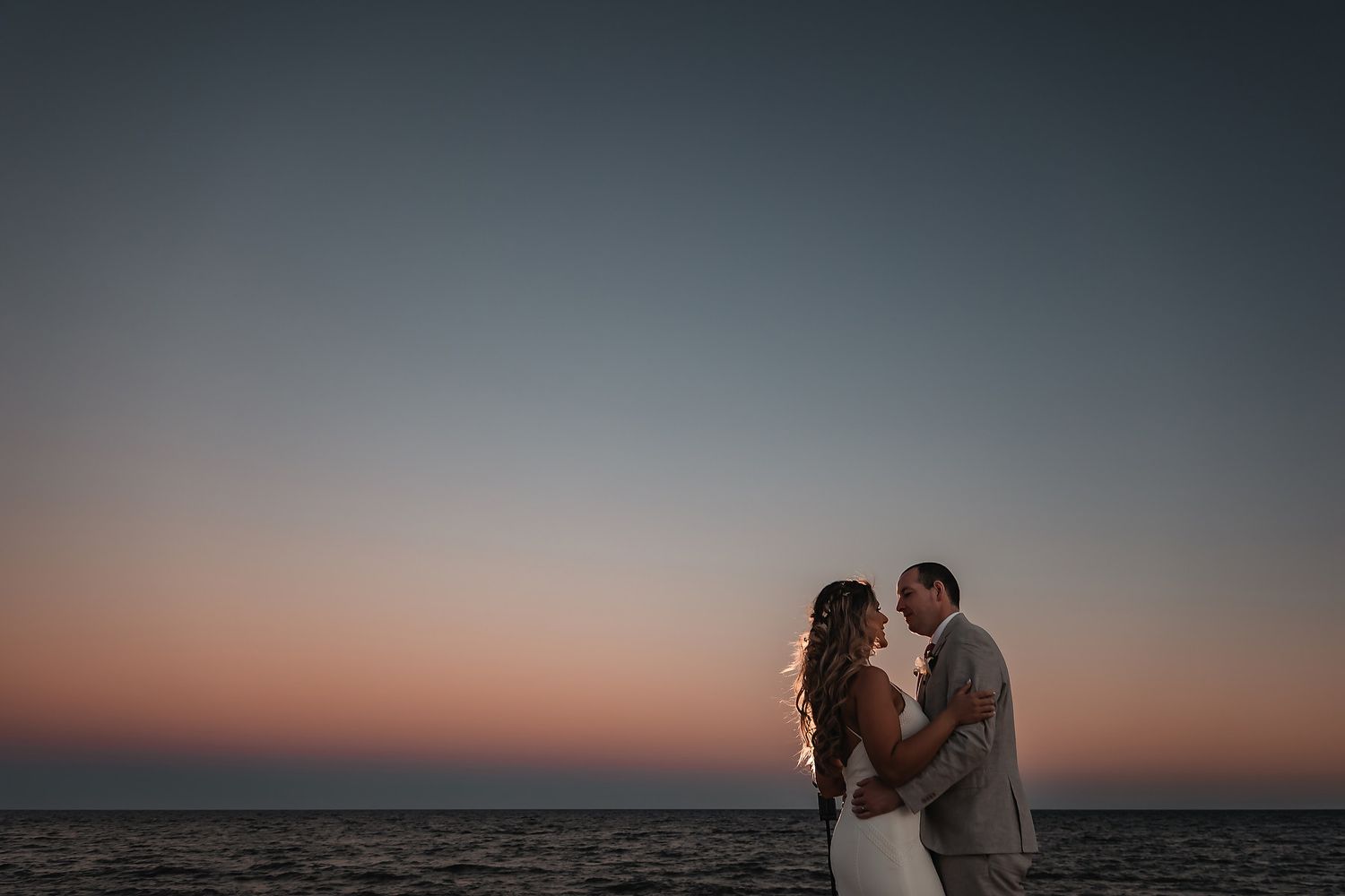 Intimate wedding portraits at dusk with the ocean horizon in the background.
