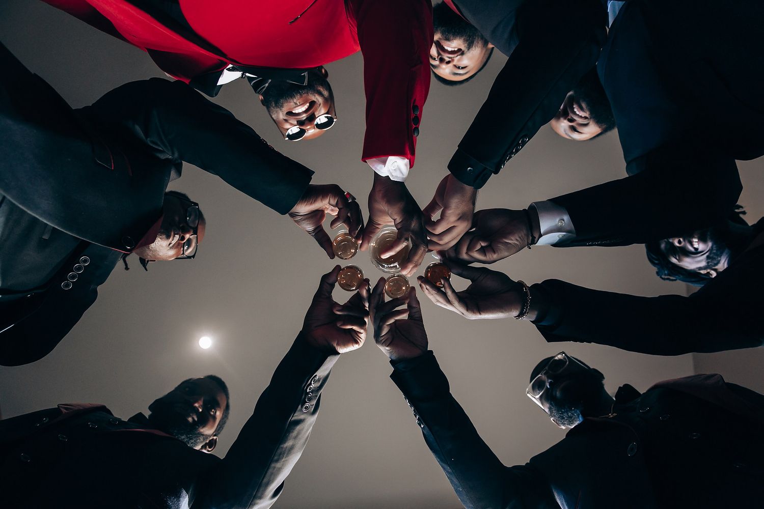 Dramatic overhead shot of people in dark clothing forming a circular pattern against a light background.