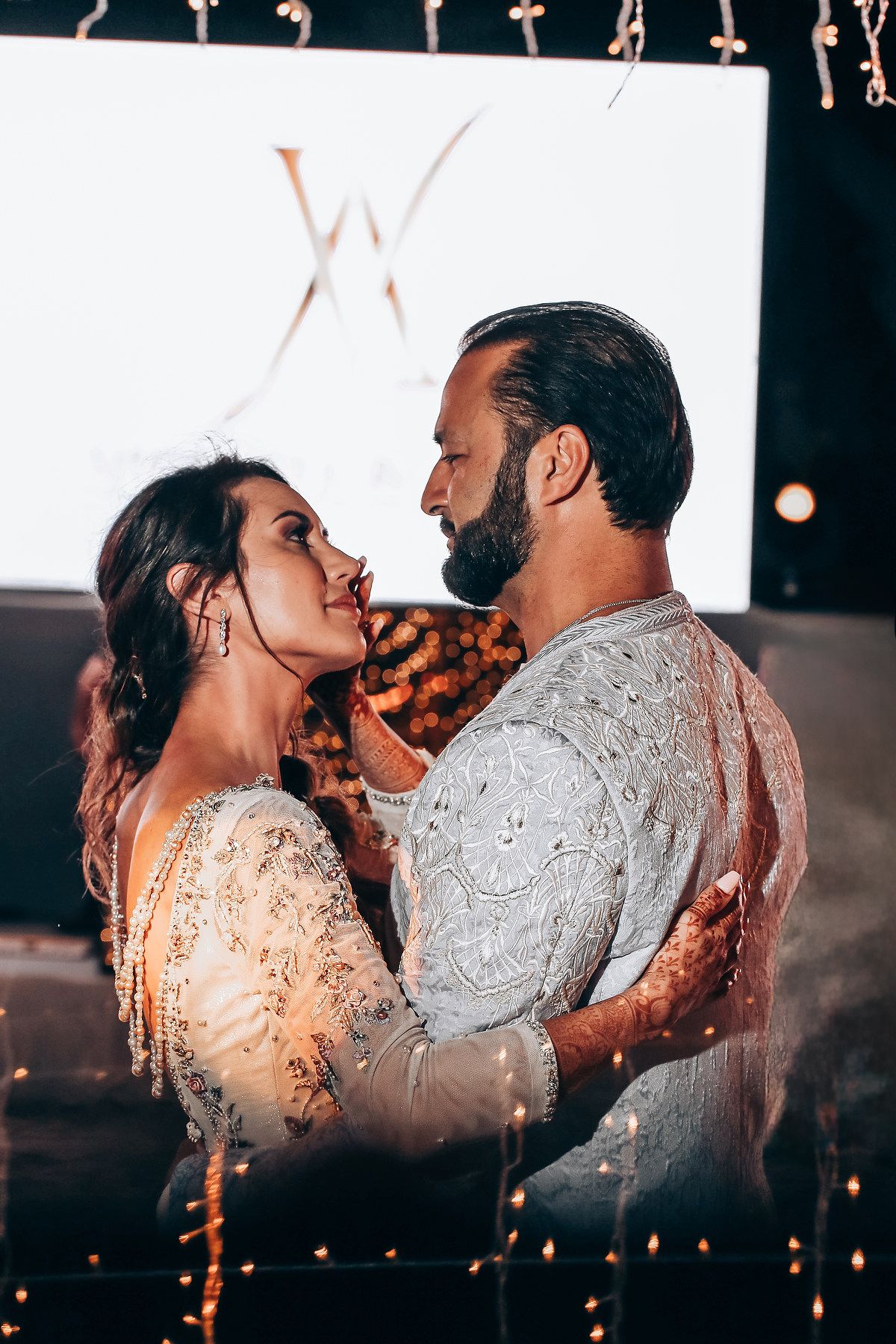 A romantic couple shares an intimate kiss under twinkling lights in a series of artistic wedding photos.