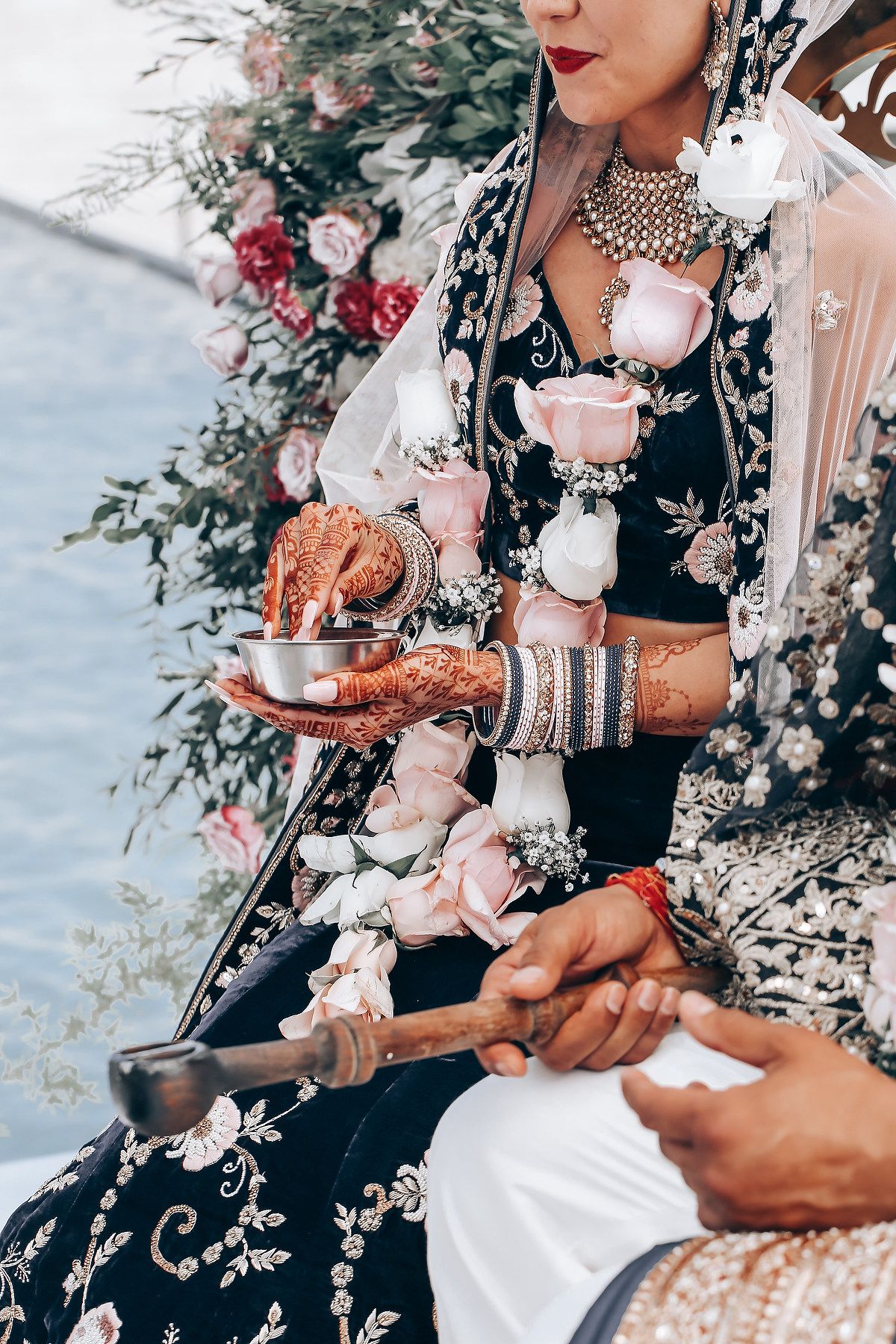 Traditional tea ceremony with ornate henna designs and floral embellishments in an elegant black and white setting.