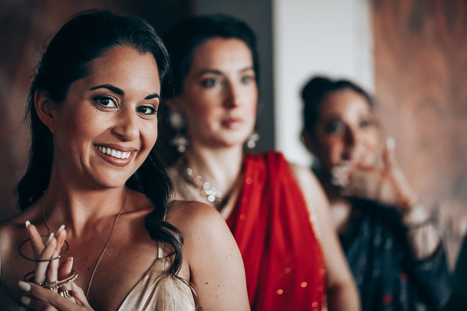 Bridesmaids in red dresses share candid moments while preparing for a wedding celebration.